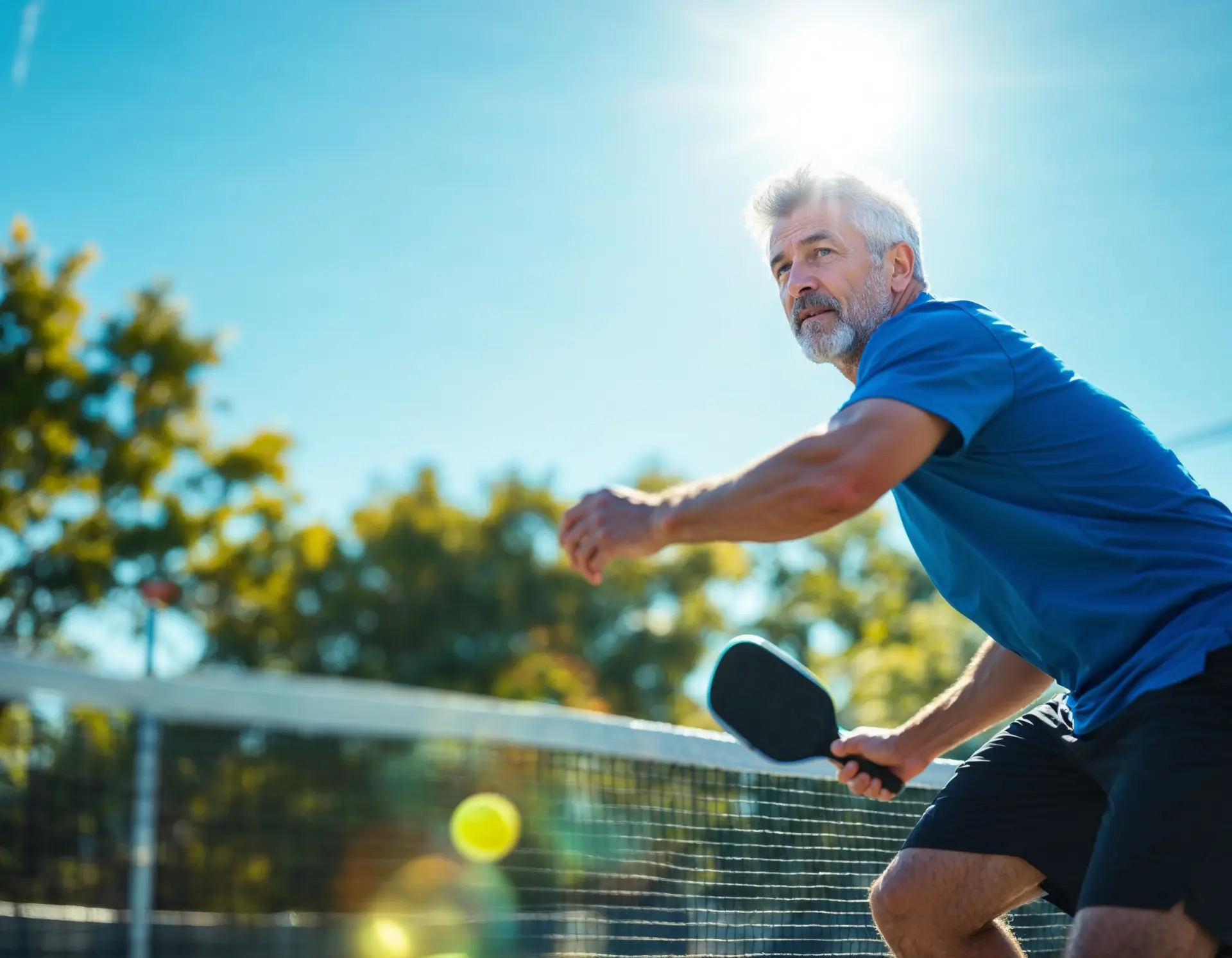 Senior man playing pickleball outdoors on sunny day